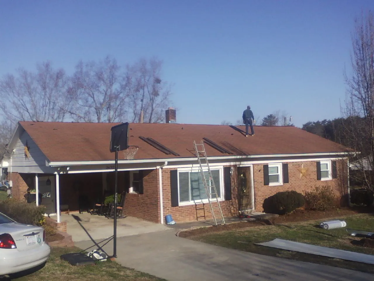 Roofer stripping a shingle roof on a brick ranch before metal panels in Dorset