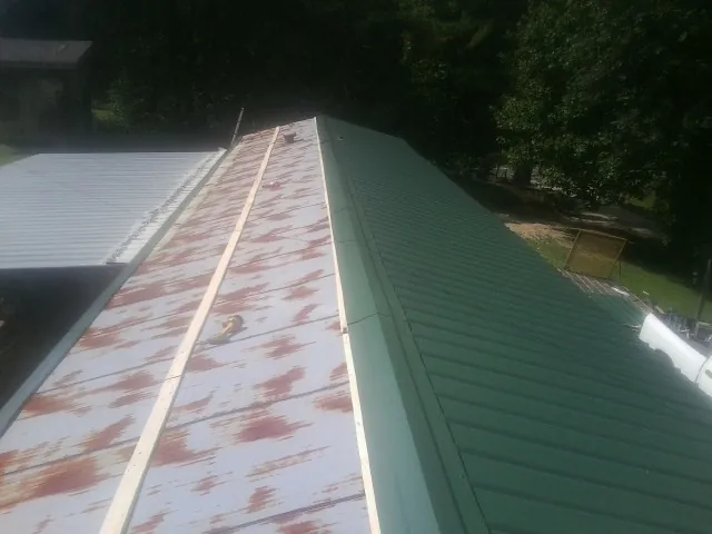 Old rusted panels beside newly installed green metal roofing — Wind Damage Roof Repair by Roofing Brothers in Dorset