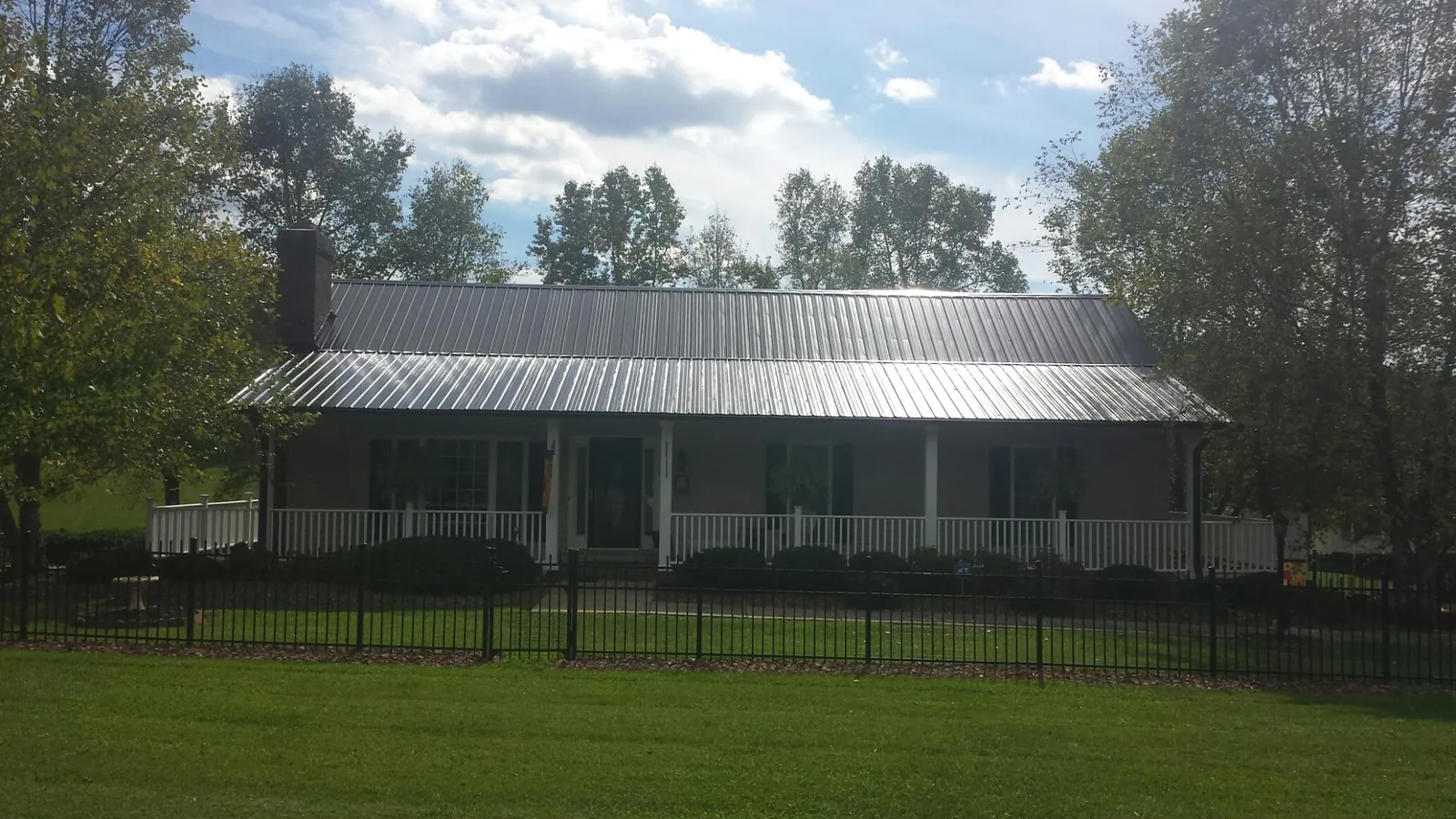 Gray metal roof on a brick ranch with a full width front porch — Gutter Guard Installation work by our crew in Dorset
