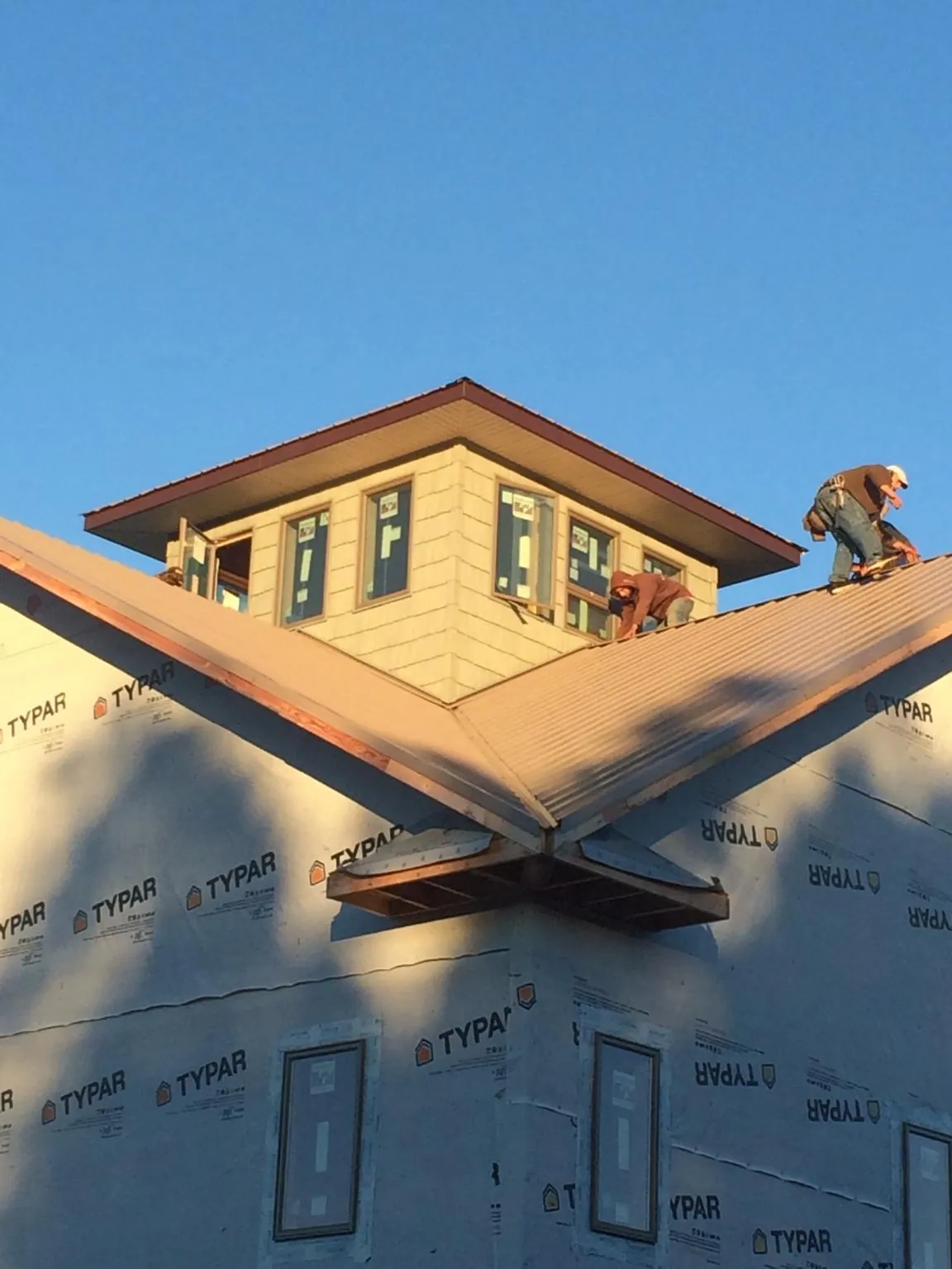 Roofers working around a rooftop cupola on a new metal roof at sunset — Roof Waterproofing in Dorset by Roofing Brothers